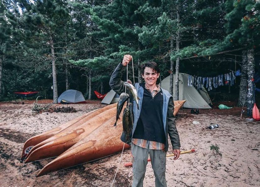 Backpacking crew preparing a meal beneath a tarp